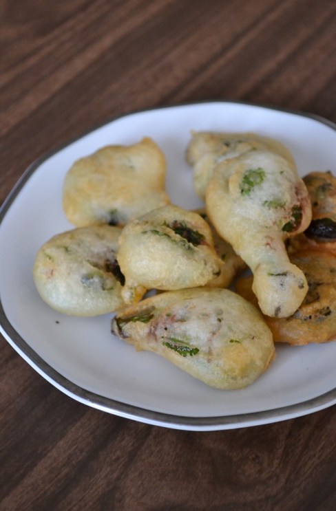 Tempura fried fiddleheads on a white plate.